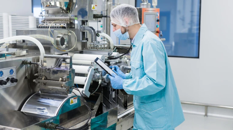 caucasian-scientist-blue-lab-uniform-configure-manufacture-machine-with-shafts-control-panel-checking-readings-making-notes.webp