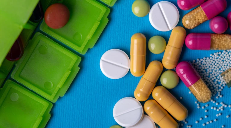 top-view-with-green-organizer-from-which-he-poured-pills-multicolored-capsules-green-white-colors.webp